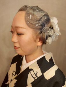 波ウェーブと前髪を活かしたレトロモダンな和装アップスタイル。白花の髪飾りを合わせた大正ロマン風アレンジ。