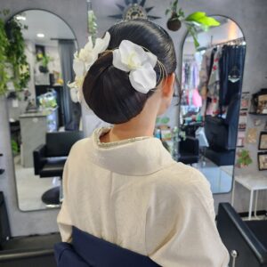 胡蝶蘭を贅沢に使用した、品格漂う和装ヘアセット。面の艶を最大限に引き出したシニヨンと、ゴールドのアクセント。結婚式や式典にふさわしい、崩れにくく洗練されたアップスタイル。