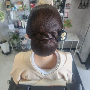 結婚式や式典にふさわしい、面を整えた和装ヘアセット。毛流れの艶を活かした低めのシニヨンに、花の装飾が美しいかんざしを合わせた、崩れにくく品格のあるアップスタイル。