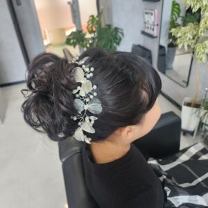 ピアノの発表会のためにセットされた、お子様の華やかなアップスタイル。高めの位置でふんわりとカールさせたお団子ヘアに、パールとシルバーのリーフモチーフが連なる上品なヘッドドレスを添えています。清楚さと可愛らしさが同居する、ステージ映えするスタイルです。