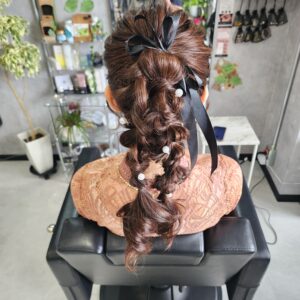 ロングヘアを活かした立体感のある編みおろし。タイトにまとめたトップから、毛先にかけてラフに崩した編み目が華やかさを演出。黒リボンとパールのアクセサリー使いがポイントの、結婚式や二次会にぴったりのパーティースタイルです。