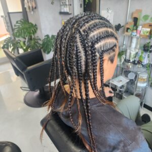 ロングヘアーの地毛を細かく編み込まれたコーンロウスタイル。